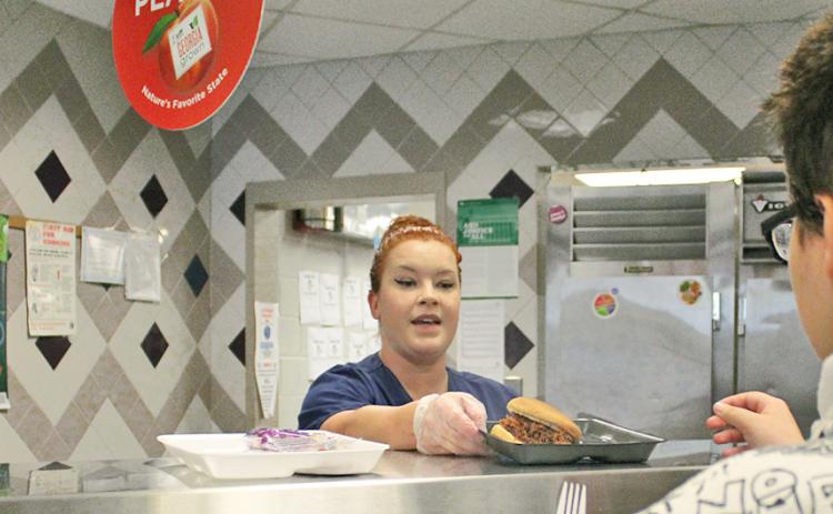 School nutrition specialist Sarah Vincze prepares a barbecue sandwich for a student at Lumpkin County High School.