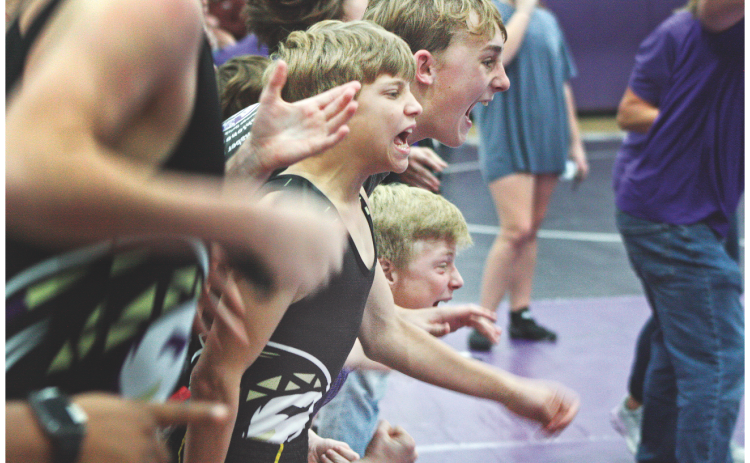 Middle school wrestlers Liam Nielson, Caleb Soles, and Alexander Nielson cheer on one of their teammates during the Lumpkin County match at Clear Creek last week.