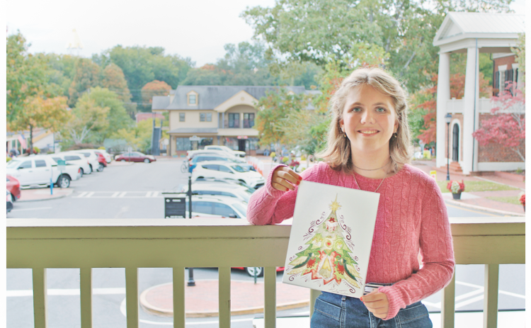 Home school student Amelia Taylor shows off her winning Christmas T-shirt design on the balcony of the Visitors Center in downtown Dahlonega.